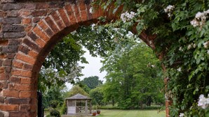 Une arche en briques menant à un belvédère dans un parc.