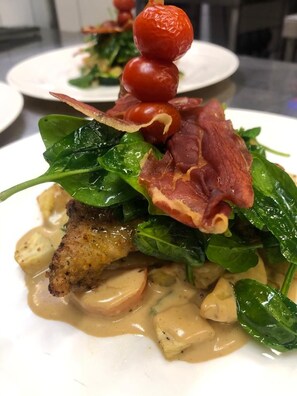 A plated dish with greens, bacon, and a cherry tomato on a skewer. - Graanzicht B&B Apartments (Midwolda)