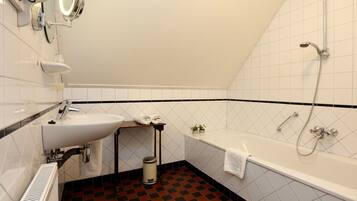 A bathroom with a sink, mirror, and shower.