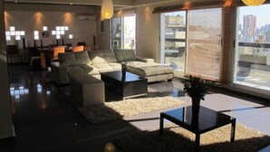 Un salón moderno con un conjunto de sofá, una mesa de centro y un amplio ventanal con vistas a la ciudad.