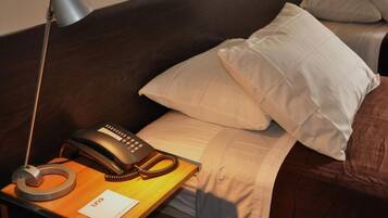 Habitación de hotel con cama, teléfono de noche, lámpara y una libreta con la palabra 'UNO' escrita.
