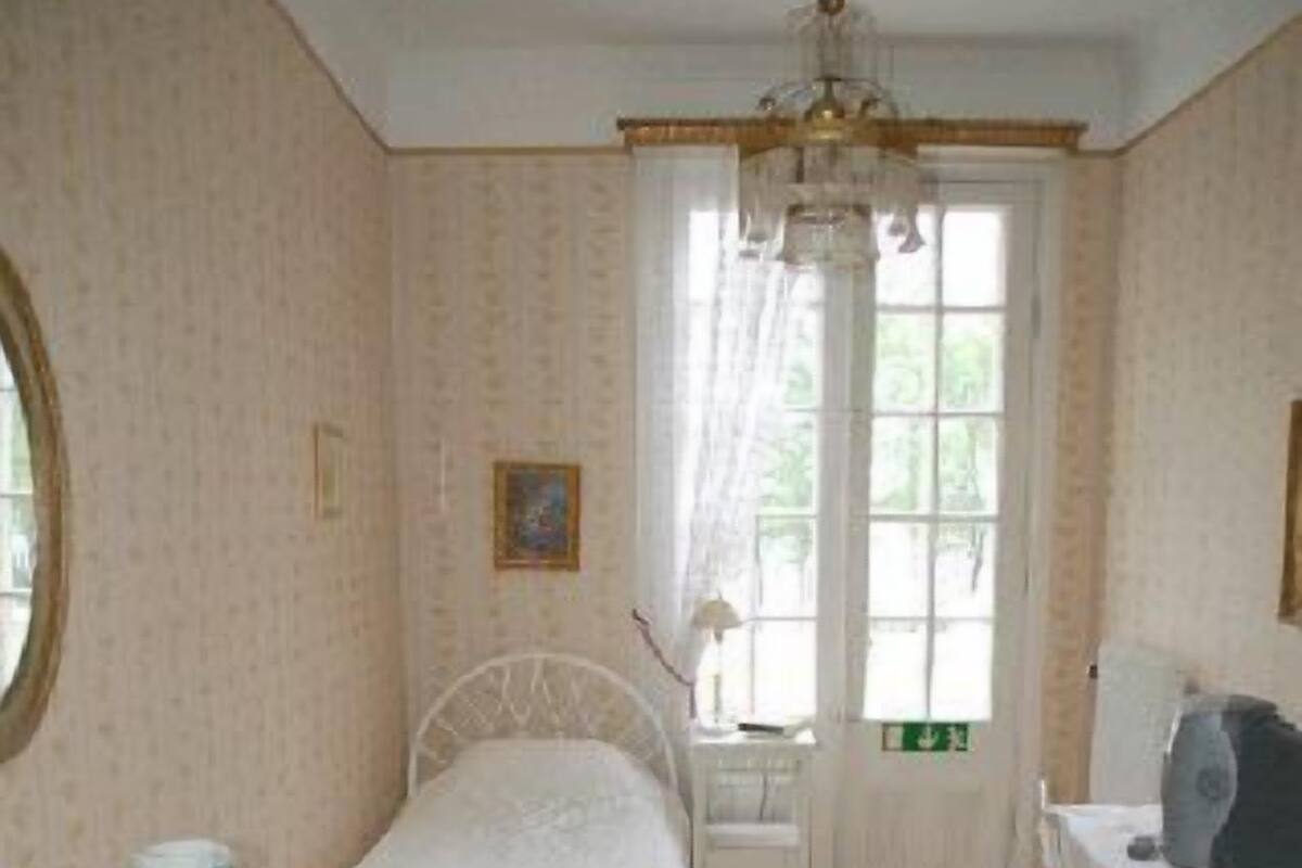 Un dormitorio con cama, cómoda, silla, escritorio y ventana con cortinas.