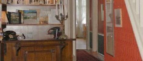 A hallway with a wooden cabinet, a clock, and a red carpet.