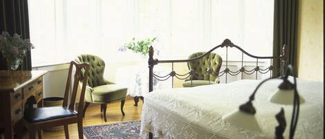 A bedroom with a large bed, two chairs, a dresser, and a chandelier.