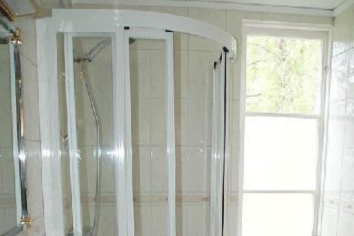 Un baño con ducha de vidrio, lavamanos y ventana.