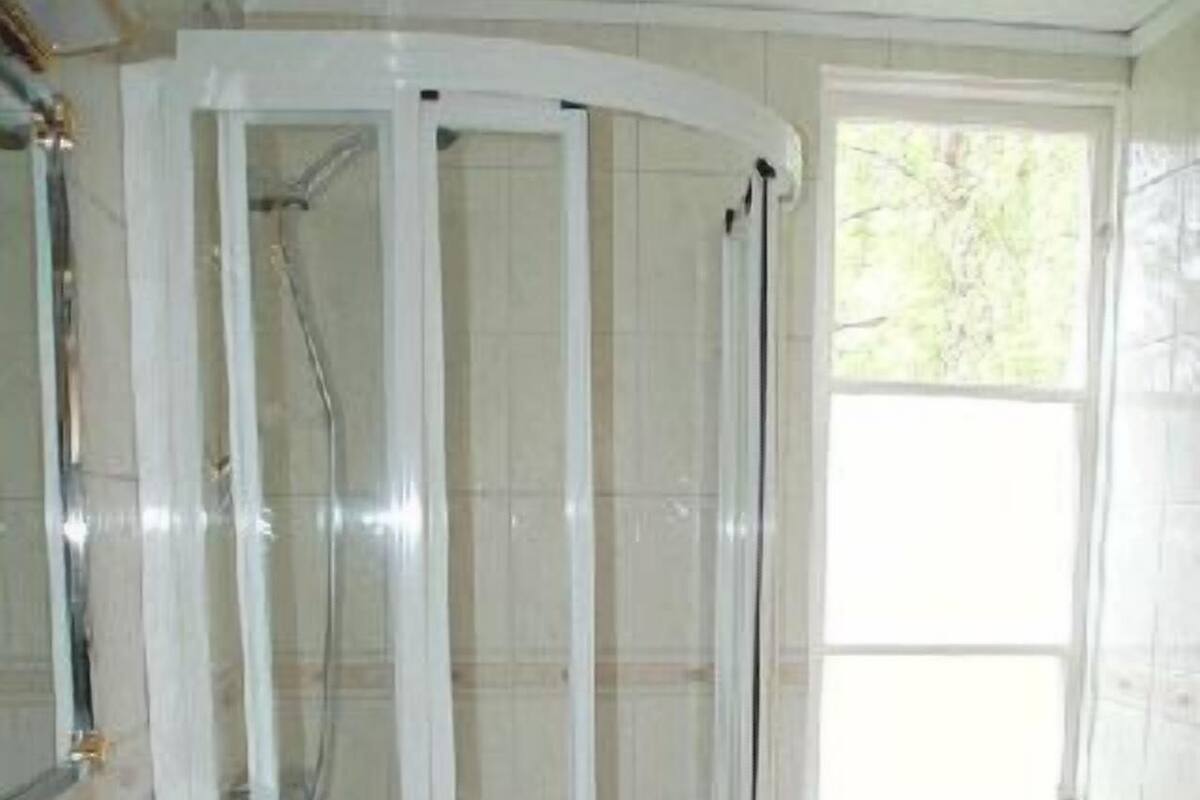 Un baño con ducha de vidrio, lavamanos y ventana.