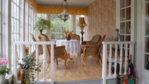 A sunlit room with a wooden floor, white railing, and a table with chairs. - Solvikens Pensionat (Ingelstad)