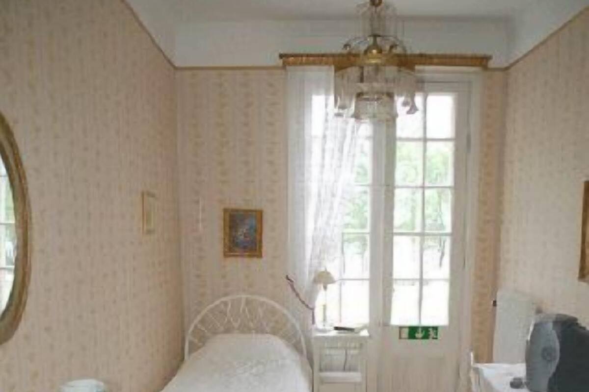 Un dormitorio con cama, cómoda, silla y ventana con cortinas.