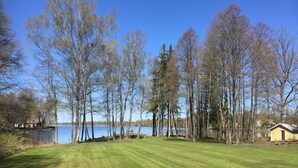 A well-maintained grassy area with a lake and trees in the background. - Solvikens Pensionat (Ingelstad)