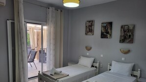 A bedroom with two beds, a balcony, and a view of the outside. - Asprokavos Beach Apartment (Corfu)