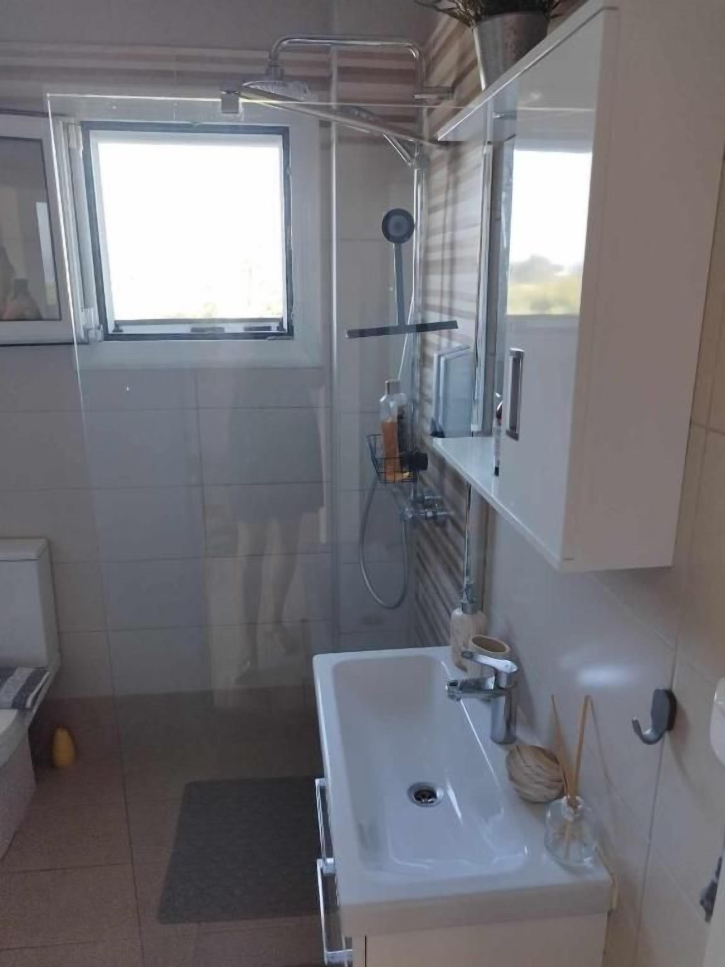 Ein Badezimmer mit Dusche, Waschbecken und Fenster.