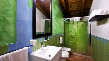 Un baño con lavamanos blanco, inodoro y cabina de ducha con mampara de vidrio.