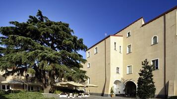 Un bâtiment doté d’une cour intérieure, d’un grand arbre et d’un espace extérieur aménagé pour s’asseoir.