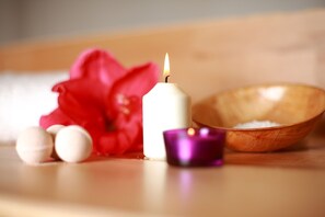 A candle, a wooden bowl, and a red flower on a wooden surface. - Relais Villa Buonanno (Cercola)