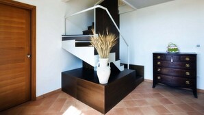 Una escalera moderna con un jarrón blanco sobre una plataforma oscura.
