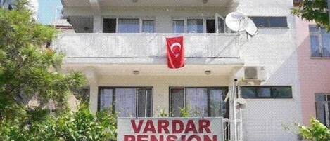 A building with a sign reading "VARDAR PENSION" and a Turkish flag.