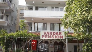Um edifício de vários andares com uma placa que diz 'VARDAR PENSION'.