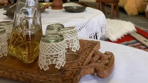 A rustic interior with a brick wall, a wooden table with a bottle and glasses, and a fireplace. - Hotel Berati (Berat)