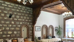 A cozy living room with a brick wall, wooden ceiling, and a colorful rug. - Hotel Berati (Berat)
