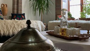 A cozy room with a rustic brick archway, a large potted plant, a metal tray with glassware, and a fluffy white sofa. - Hotel Berati (Berat)