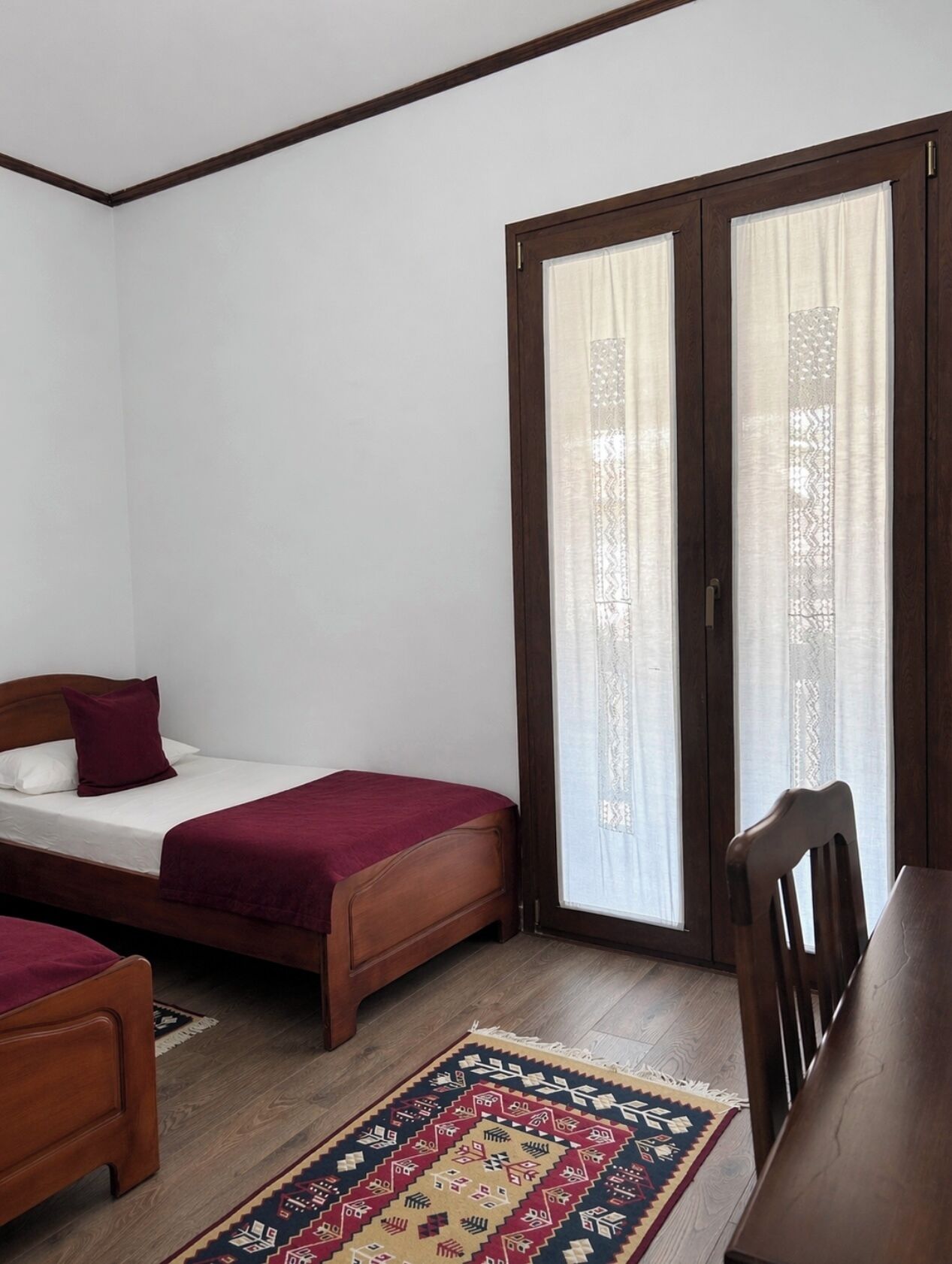 A room with a bed, a chair, a table, and a window with curtains.
