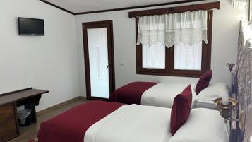 Un dormitorio con dos camas, televisión, escritorio de madera y ventana con cortinas de encaje.