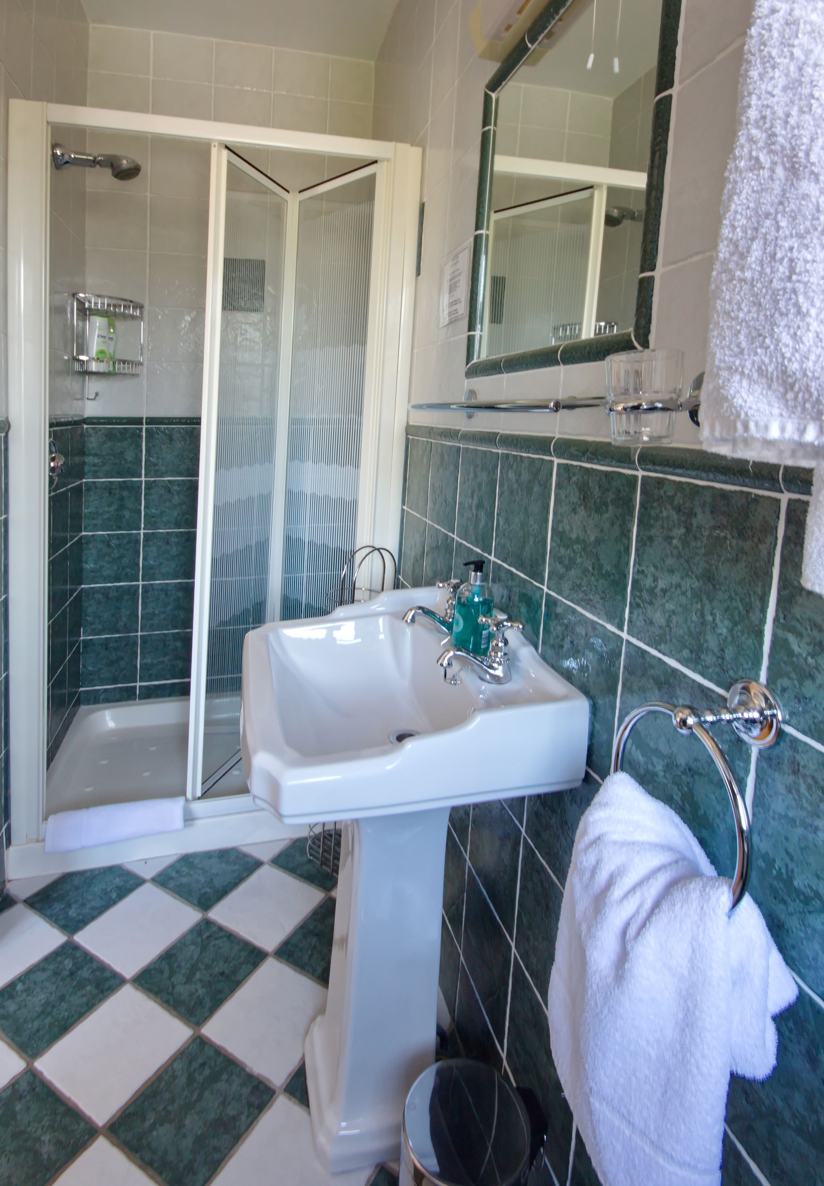 Un baño con ducha, lavamanos y espejo.