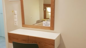 Un baño moderno con tocador de madera, una silla verde, un espejo grande y un cartel que indica prohibido fumar.