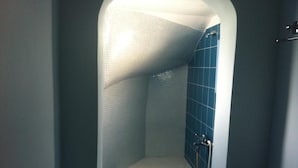 Un espacio de ducha pequeño y cerrado, con azulejos azules y techo blanco.