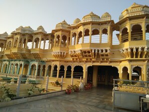 A traditional building with ornate architecture, multiple balconies, and a courtyard with potted plants. - Chunda Palace (Udaipur)