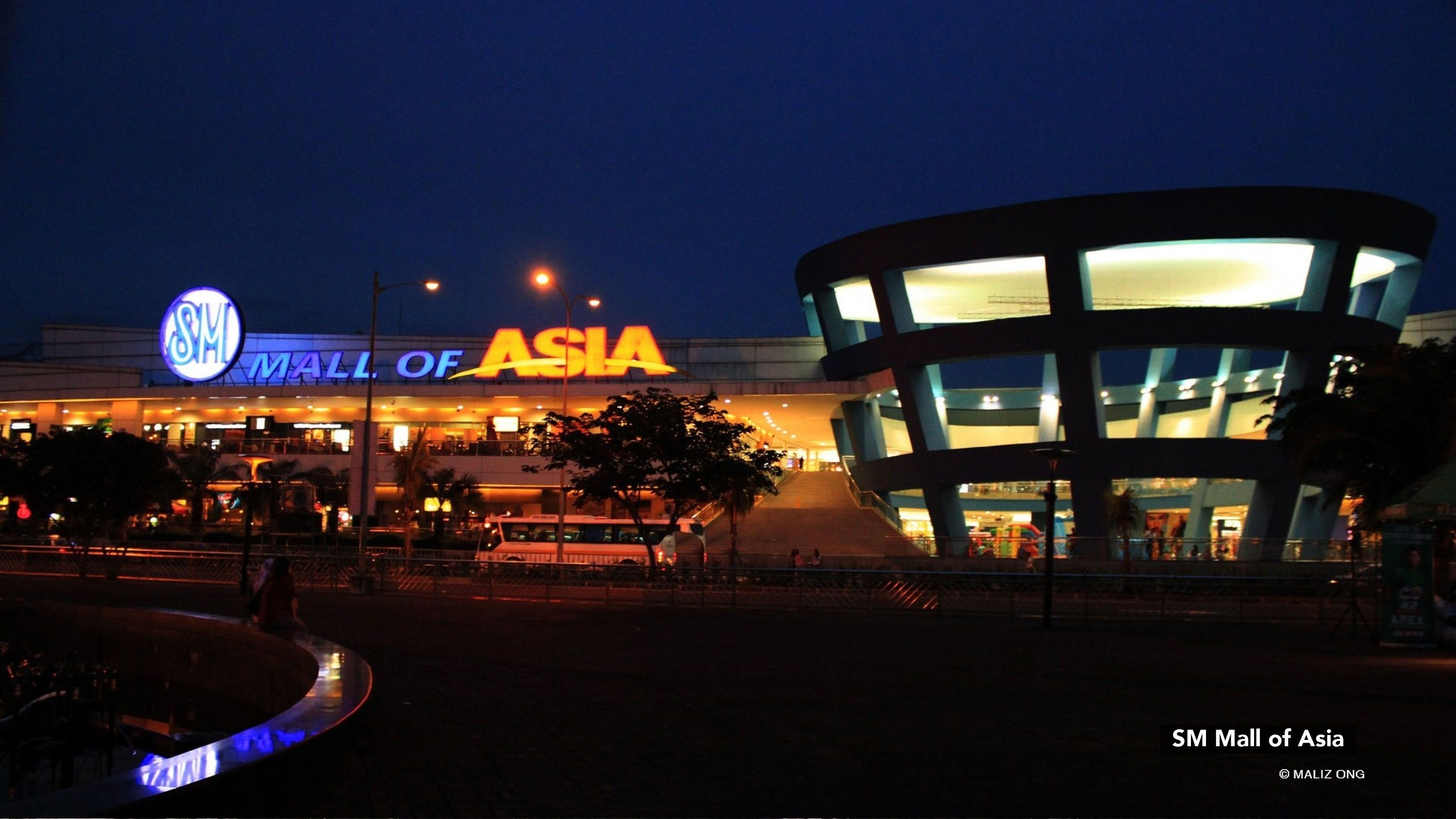 L'esterno del centro commerciale SM Mall of Asia, con insegne illuminate e una struttura moderna.