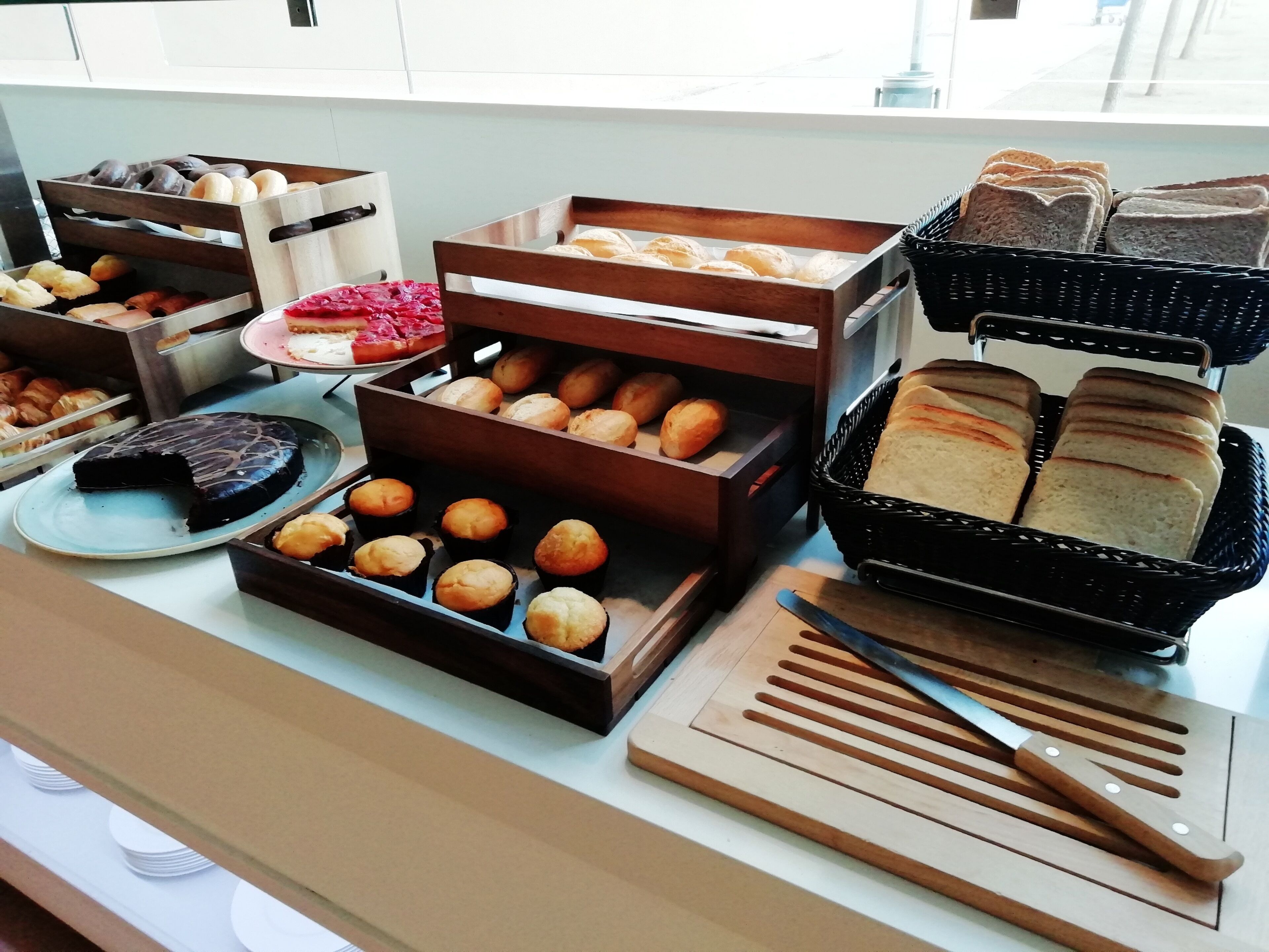 A buffet with various baked goods, including bread, pastries, and a cake.