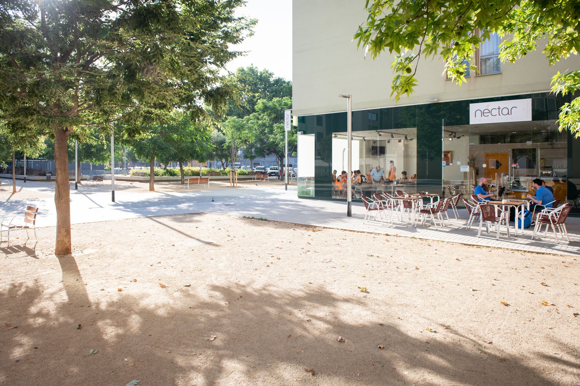 An outdoor seating area with tables and chairs in front of a building with a 'nectar' sign.