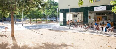 An outdoor seating area with tables and chairs in front of a building with a 'nectar' sign.