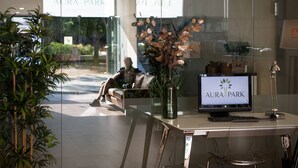 Un comptoir d’accueil avec un écran d’ordinateur affichant le texte « AURA PARK » et un vase contenant des fleurs séchées.