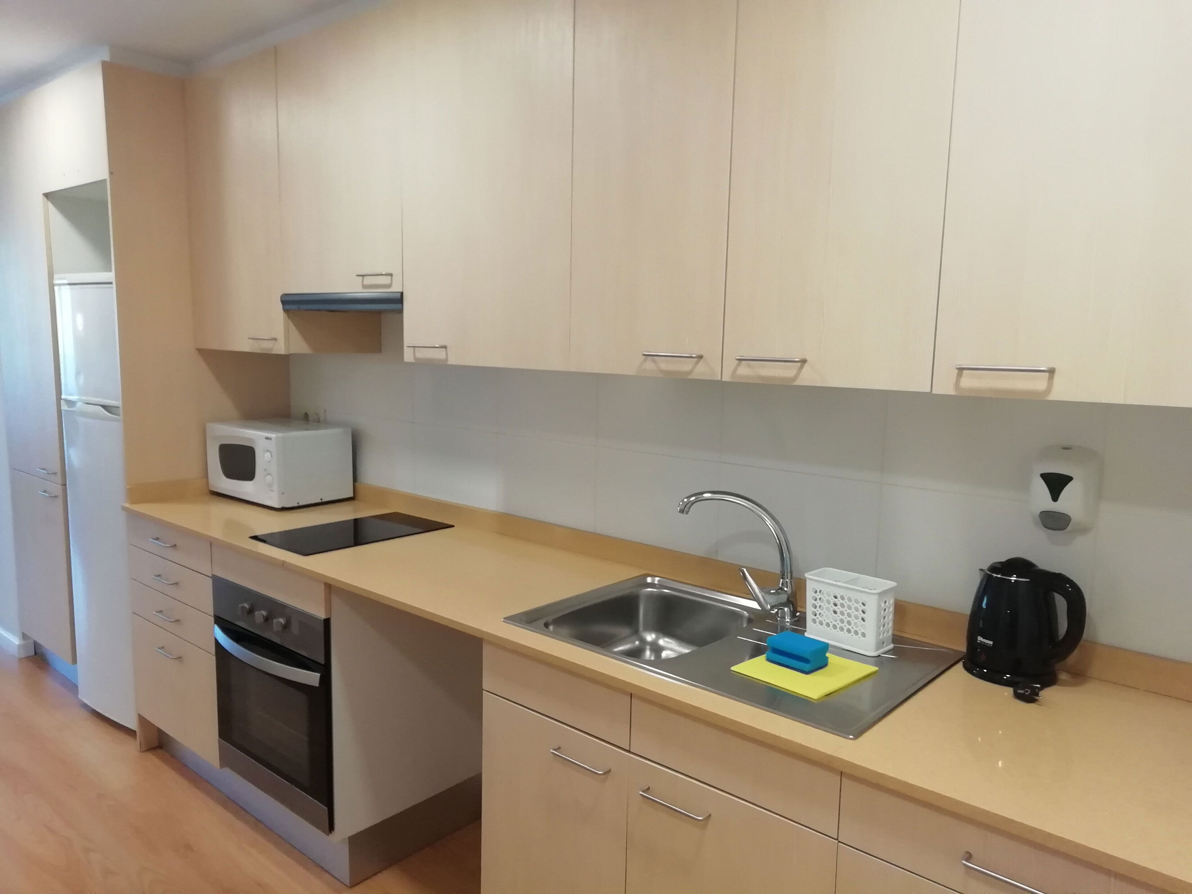 A modern kitchen with a microwave, oven, sink, and coffee maker.