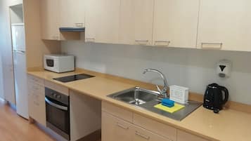 A modern kitchen with a microwave, oven, sink, and coffee maker.