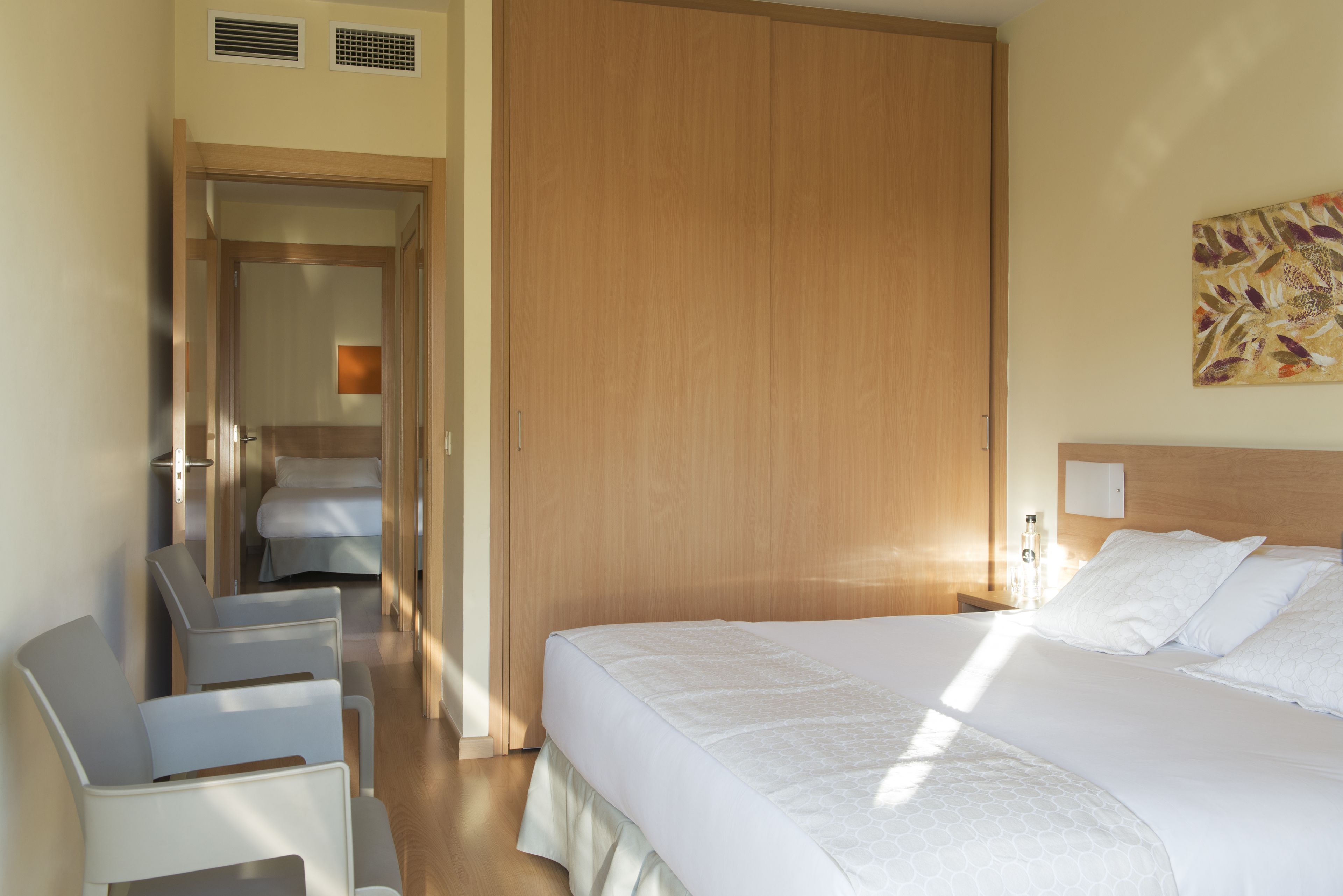 A hotel room with a bed, a desk, and a wardrobe.