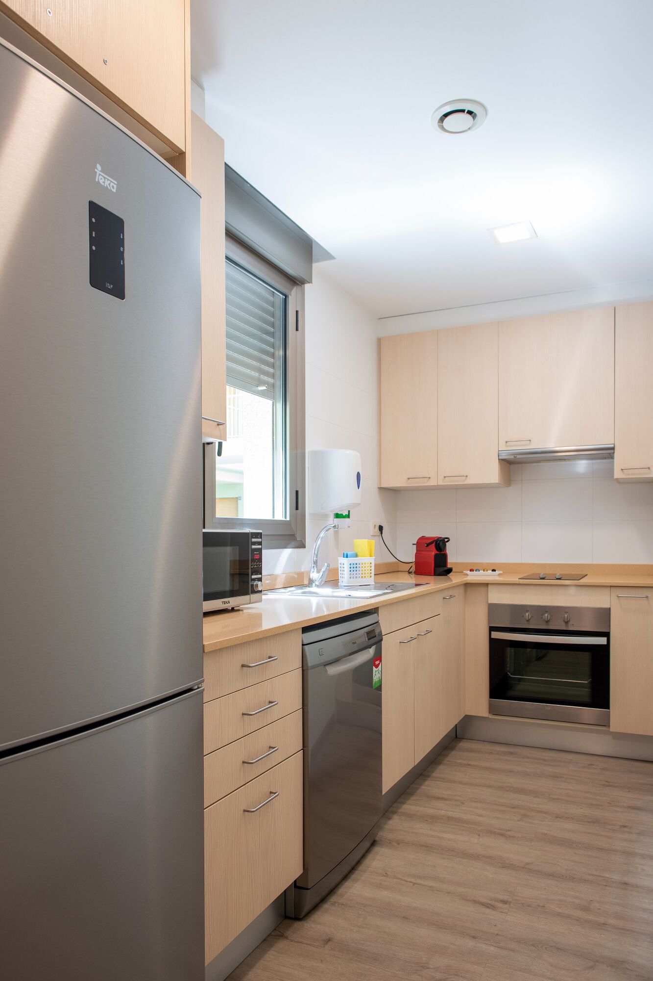 Una cocina moderna con electrodomésticos de acero inoxidable, armarios de madera y lavavajillas.
