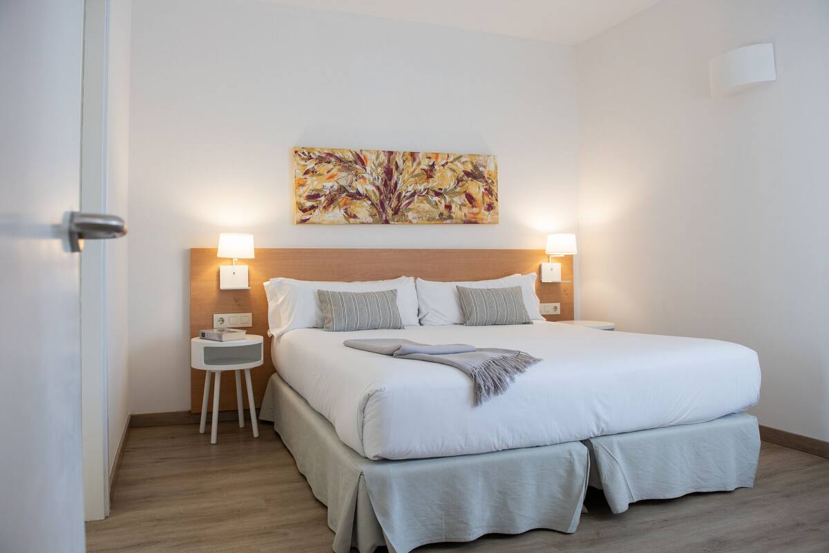 Hotelkamer met een groot bed, twee nachtkastjes, een wanddecoratie en een deur.