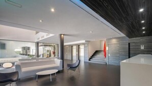 Een moderne lobby met een receptiebalie, een zithoek en een trap.