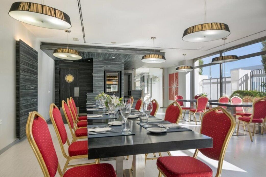 A conference room with a long table, red chairs, and modern pendant lighting.