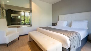 Een moderne slaapkamer met een groot bed, een bankje, een stoel en een groot raam.
