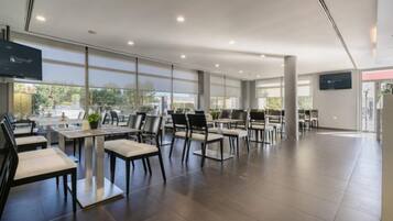 A spacious, modern dining area with high ceilings and large windows, featuring a clean, minimalist design with black and white furniture.