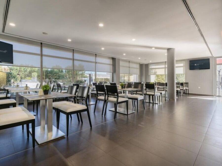 Un comedor amplio y moderno con techos altos y ventanas grandes, que presenta un diseño limpio y minimalista con mobiliario blanco y negro.