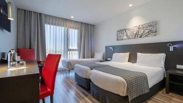 A hotel room with a bed, two bedside tables, a desk with a chair, and a large window with curtains.