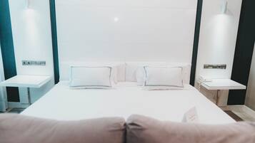 Habitación de hotel con una cama grande, dos mesitas de noche y una lámpara de pared.