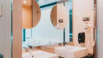 Une salle de bain moderne avec deux lavabos, un grand miroir et une douchette à main.