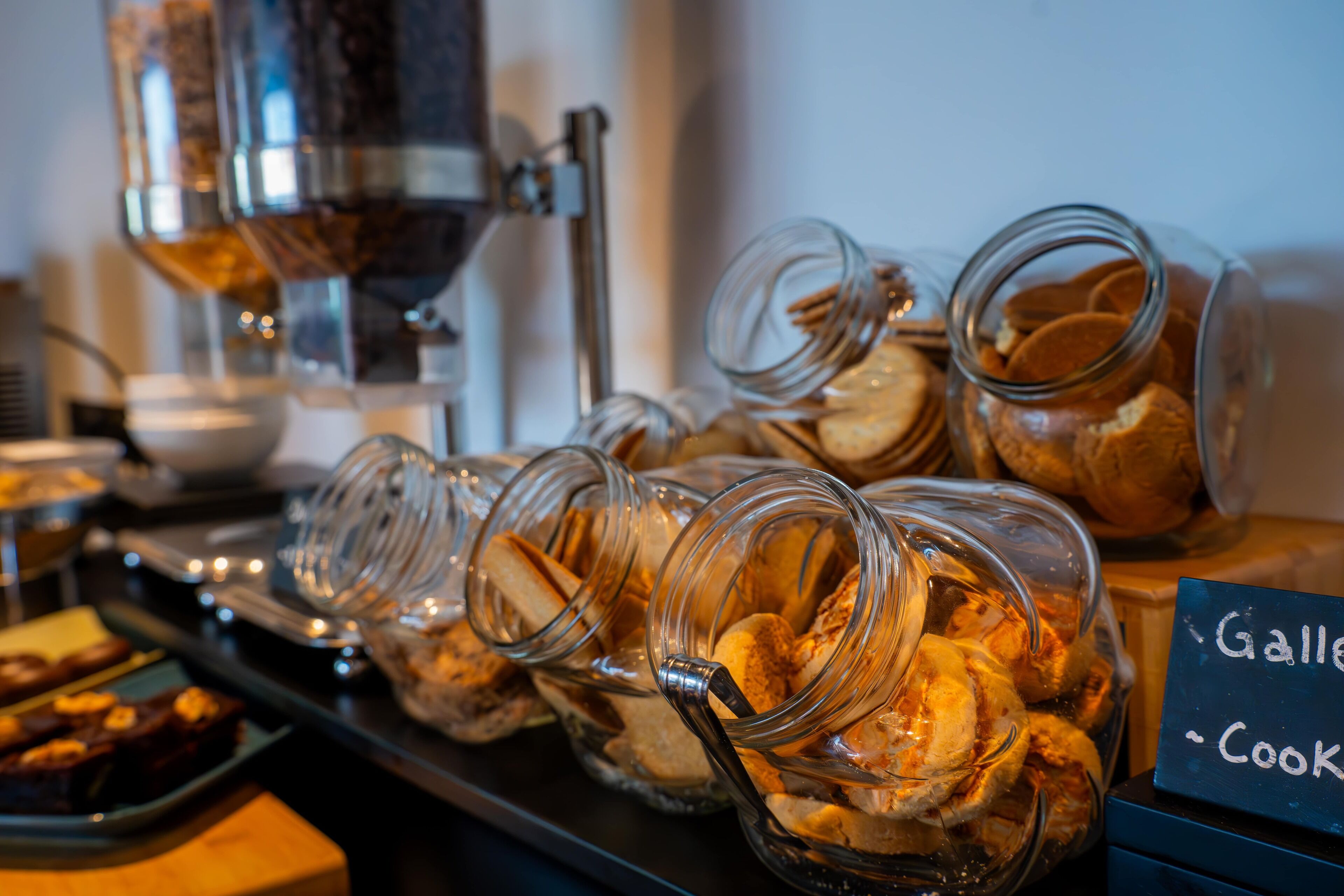 A bakery display with jars of cookies and a coffee machine in the background.