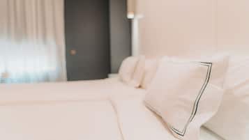 A neatly made bed with white linens and a pillow with a dark trim.